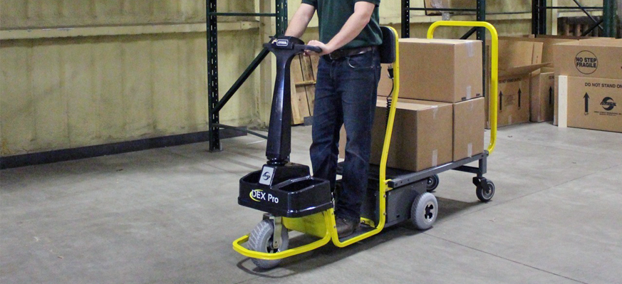 Warehouse worker riding an industrial standing platform cart.